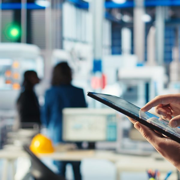 Mãos de um engenheiro a utilizar um tablet para monitorizar o software de diagnóstico numa fábrica