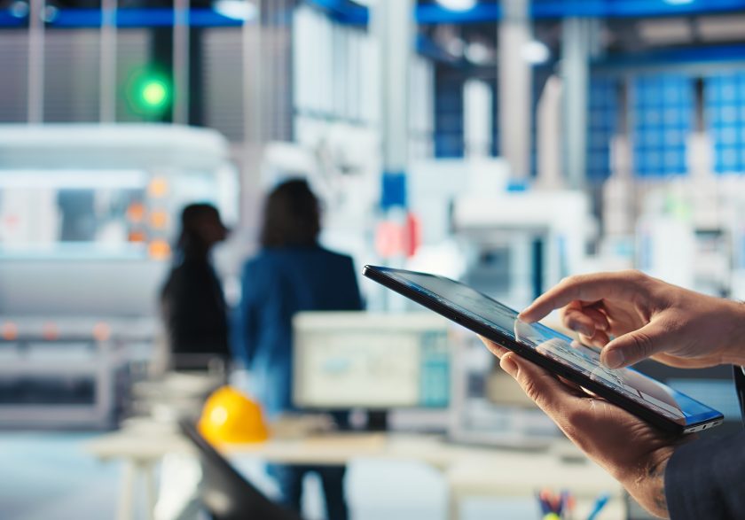 Mãos de um engenheiro a utilizar um tablet para monitorizar o software de diagnóstico numa fábrica